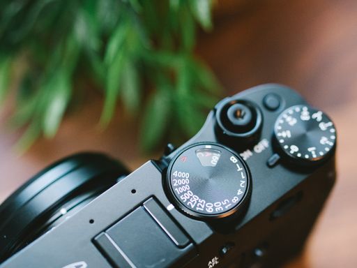 A high angle closeup of the mode dial of a camera on the table under the lights