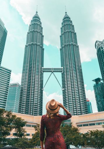 A vertical shot of a woman enjoying the view of the KLCC Park in Kuala Lumpur, Malaysia