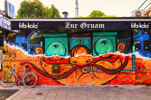 Vibrant street art mural on a building facade in an urban setting with a bicycle parked in front.