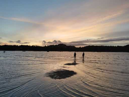 Scenic view and silhouette of people walking around the sea bed at low tide at sunset at a Choeng Mon Beach, on the island of Koh Samui in Thailand