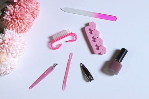 A top view of nail care items isolated on a white surface near beautiful pink flowers