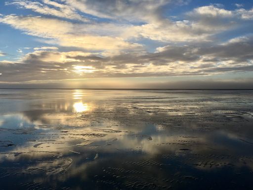 A landscape of the sea with clouds reflecting on the water during the sunrise in the morning