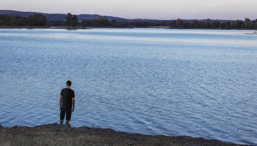 A beautiful shot of a male standing on the beach and looking to the horizon