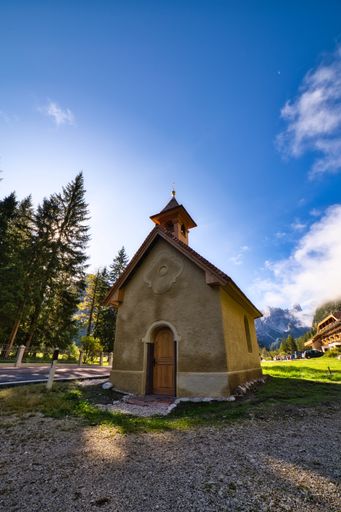 A vertical shot of beautiful scenery of the Dolomites and a chapel in the middle, Italy