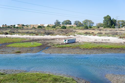 Abandoned boat at the mouth of a river, close to the sea