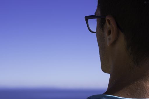 A closeup selective focus shot of a male looking to the horizon over the sea