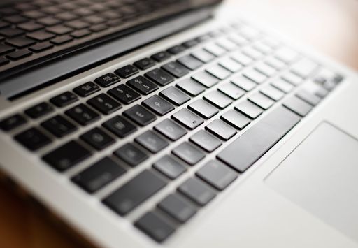 A high angle shot of a silver and black laptop on a wooden table