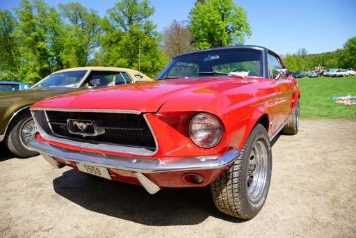 Front view of a red classic Ford Mustang parked on the street among other cars