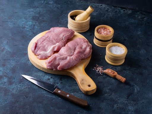 A closeup shot of row steak meat with seasonings on a black background