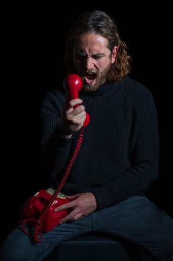 A Caucasian nervous man with a red telephone