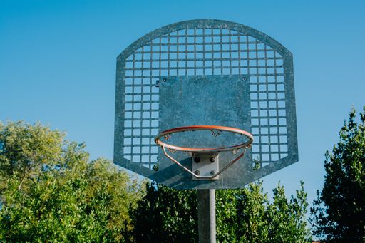 A low angle shot of a basketball hoop under a clear blue sky