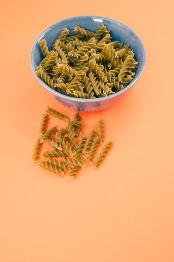 Vertical shot of  italian fusilli pasta in a blue bowl on an orange tabletop with text space