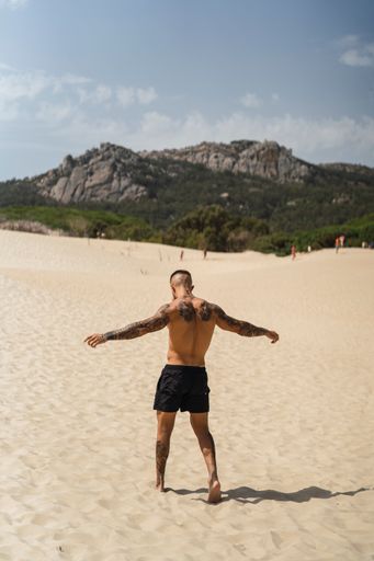 A back view of a handsome man with tattoos enjoying his vacation on the beach