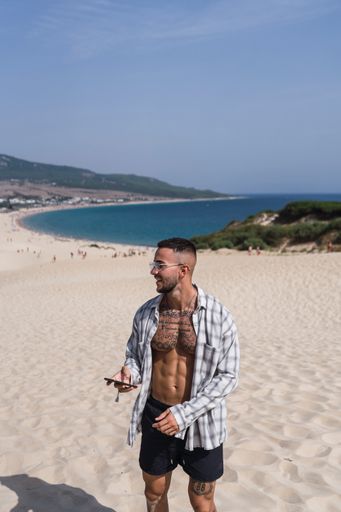 A handsome, half-naked, caucasian man walking on the sand enjoying his vacation