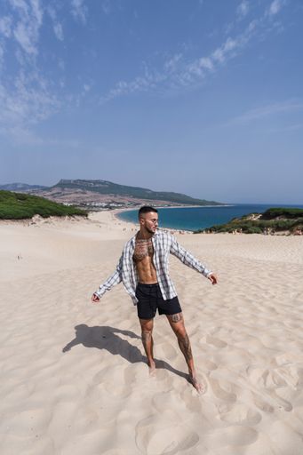 A handsome, half-naked, caucasian man walking on the sand enjoying his vacation