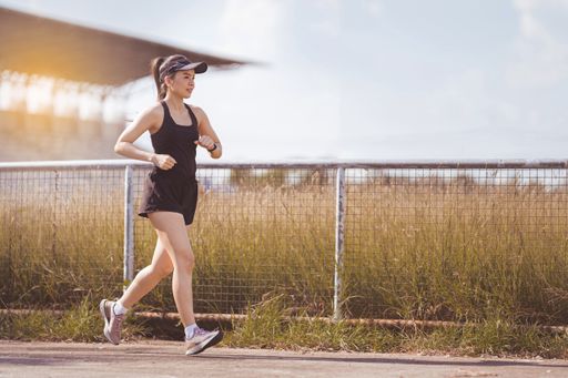 A young woman jogging outdoors in the city park on a beautiful summer day.