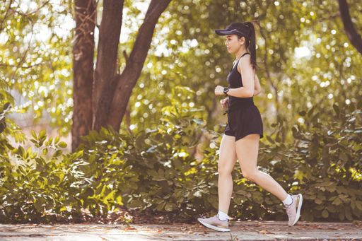 A young woman jogging outdoors in the city park on a beautiful summer day.