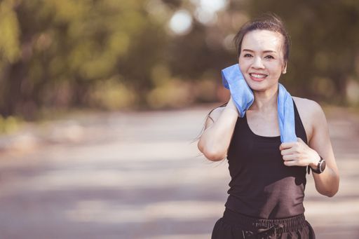 A young woman jogging outdoors in the city park on a beautiful summer day.