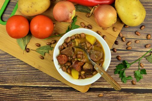 A top view shot of a wooden table with vegetables and soup made from it