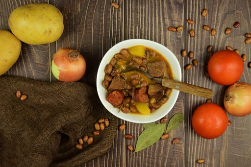 A top view shot of a wooden table with vegetables and soup made from it