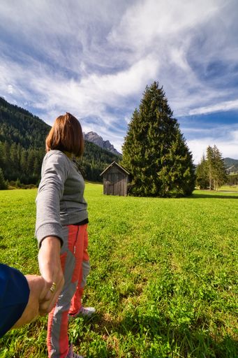 A beautiful shot of a young woman and an old wooden barn in a field