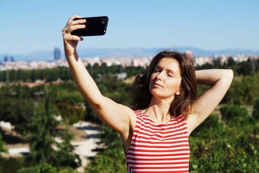 A young Caucasian female in a striped dress taking a selfie in Madrid, Spain