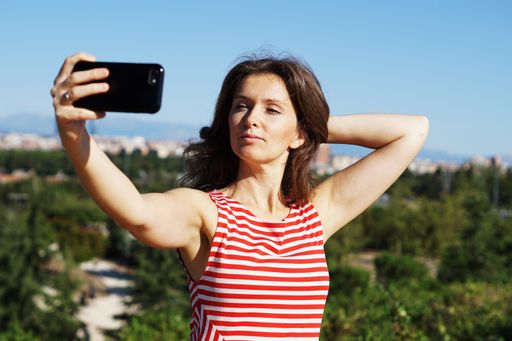 A young Caucasian female in a striped dress taking a selfie in Madrid, Spain
