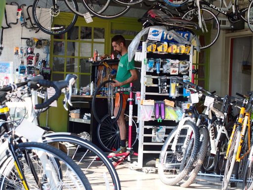 A horizontal shot of a bicycle shop and repairing service. A male wheel in hand. Kanas, US