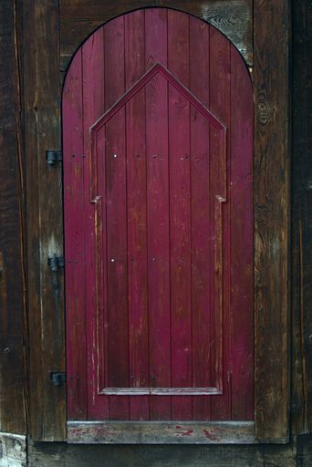 A vertical shot of an old wooden purple-painted door.