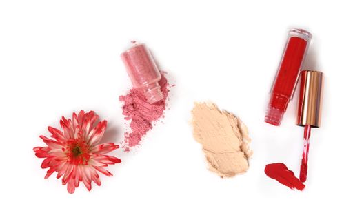 A top view shot of foundation, liquid lipstick and glitter cosmetics isolated on White Background