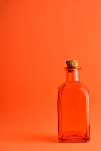 A vertical shot of a transparent bottle isolated on a red background