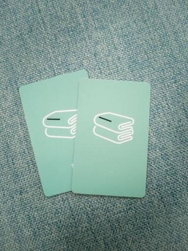A vertical shot of two minimalistic library cards on a sofa