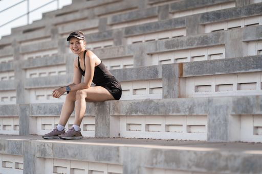 A healthy adult Asian female running up on concrete stairs of the city stadium