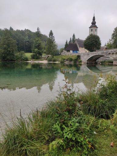 A vertical shot of Bohinj Lake, church, bridge in the background. Triglav National Park, Slovenia.