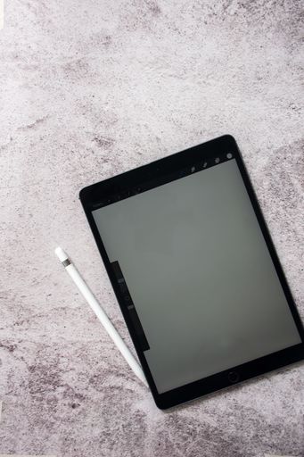 A digital tablet with a stylus on a textured surface, ideal for creative work and digital art.