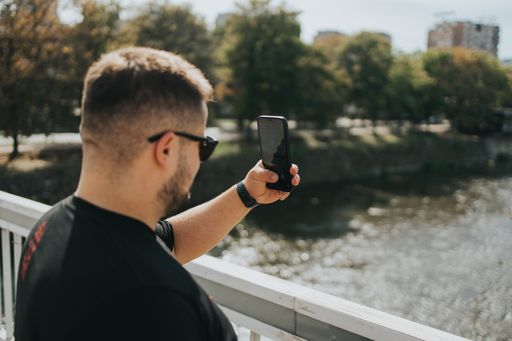A white Caucasian guy taking a picture of a landscape from the bridge