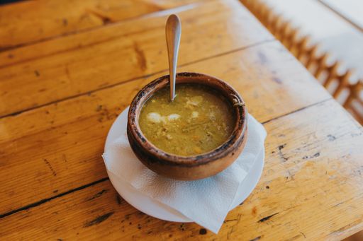 A bowl of soup served on the table with a white saucer