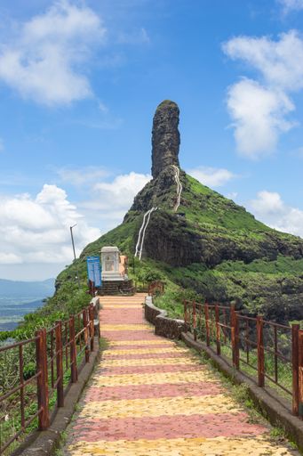 A vertical shot of a path in a scenic mountainous area under the cloudy sky