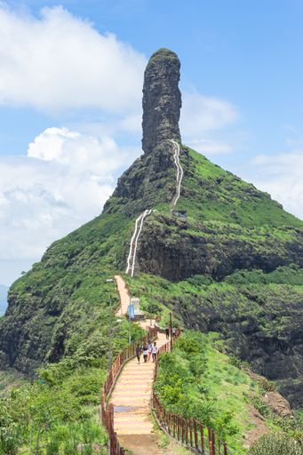 A vertical shot of a path in a scenic mountainous area under the cloudy sky
