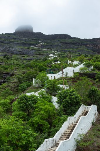 A vertical shot of stairs in a scenic mountainous area under the cloudy sky