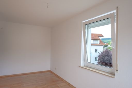 An unfurnished room with parquet flooring and a window