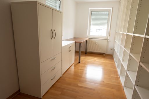 An office room with a white rack cupboard and desk
