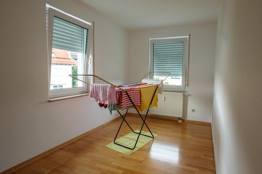 A clothes horse with laundry in a room with windows