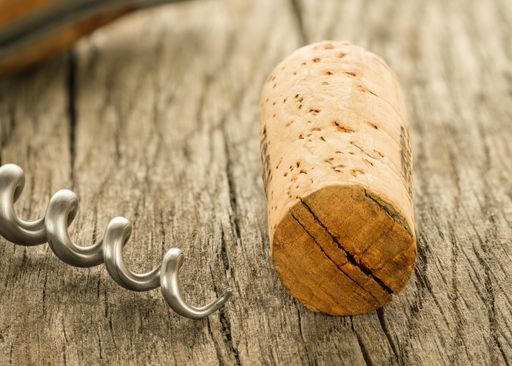 A cork and spindle of a corkscrew on a wooden board