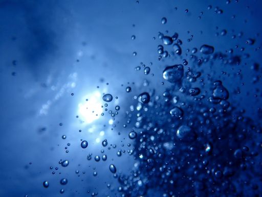 A closeup of bubbles popping up from under the blue ocean