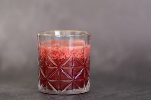 A fresh berries smoothie in a glass on a gray background