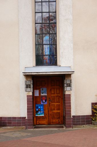 A vertical shot of an old wooden entrance door to a church in the Stare Zegrze district during daytime