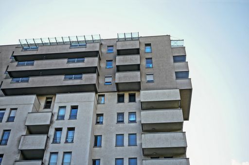 A low-angle shot of the Pelikan apartment building against a blue sky in the Piastowskie area