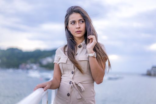 A young beautiful brunette woman posing near the sea during windy weather in San Sebastian, Spain