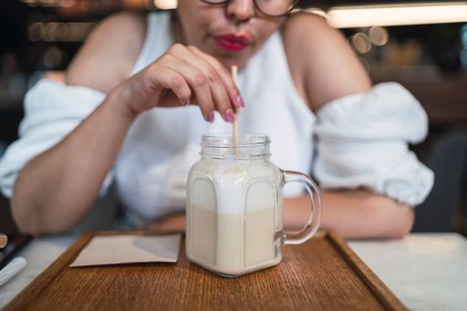 A female drinking a cold beverage served in a glass jar